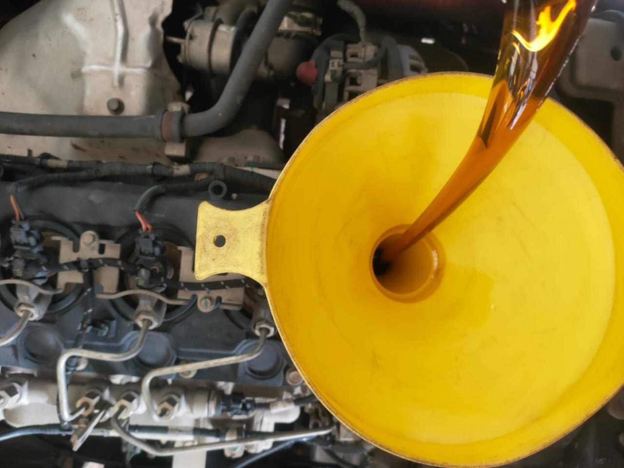 Diesel oil change using a yellow colored funnel.